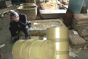 An Iraqi
                  mourns the destruction of priceless cultural artifacts
                  behind untouched oil barrels.